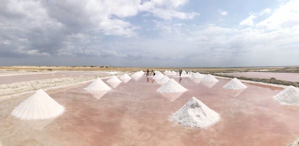 Panoramic view of people on sand against sky