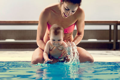 Smiling mother and son swimming in pool