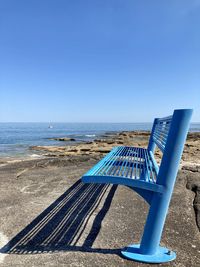 Deck chairs on beach against clear blue sky