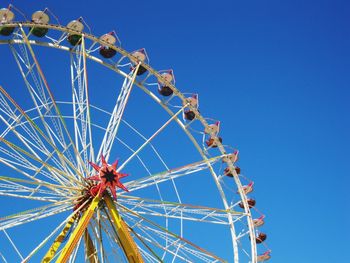 Low angle view of ferris wheel against clear blue sky