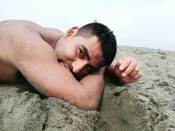 Portrait of young woman lying on sand