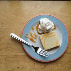 Directly above shot of lemon tart with whipped cream in plate on table