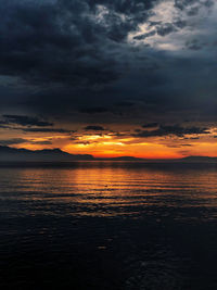 Scenic view of sea against dramatic sky during sunset