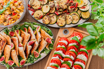 Overhead shot multiple platters of colorful mediterranean and italian themed foods.