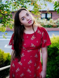 Portrait of beautiful young woman standing against trees