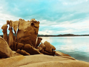 Rock formation on beach against sky