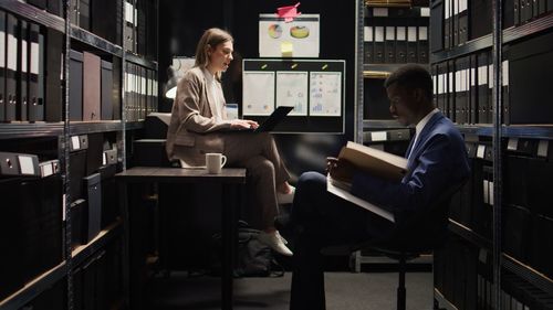 Rear view of woman using digital tablet while sitting in office