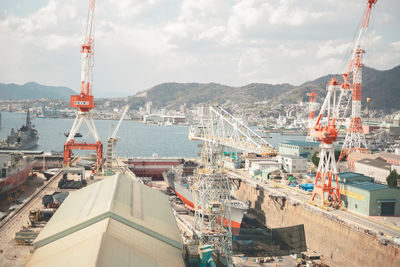 High angle view of cranes and buildings against sky