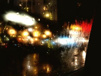 Defocused image of illuminated road seen through wet window