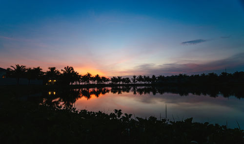 Silhouette trees by lake against sky during sunset