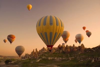 Hot air balloons flying over landscape against sky during sunset