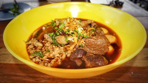 Rice noodle soup with stewed pork  in yellow bowl.