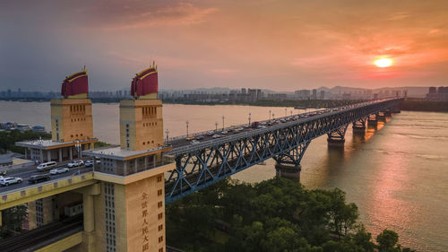 Bridge over river against sky during sunset