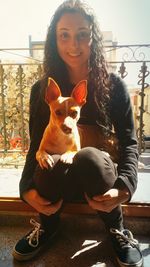 Portrait of smiling young woman holding cat in city