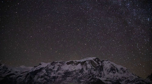 Low angle view of snowcapped mountains against sky at night