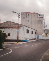 Road by buildings against sky in city