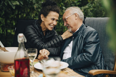 Happy senior man and woman holding hands while sitting at dining table