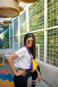 Portrait of smiling young woman standing against building