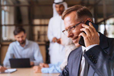 Side view of young man using mobile phone in office