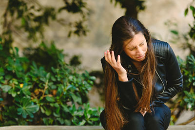 Young woman sitting against plants