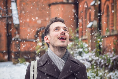 Mid adult man with mouth open looking up during snowfall