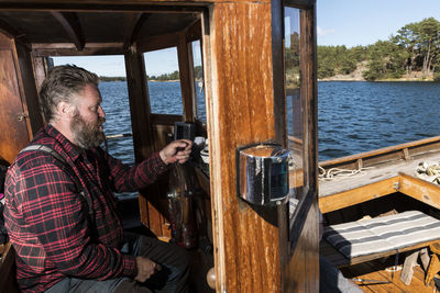 Man in the wheelhouse steering a wooden boat