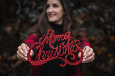 Woman holding red merry christmas text