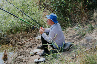 One young man puts a worm on a fishing rod hook.