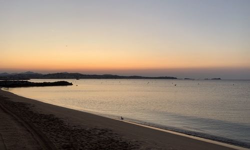 Scenic view of beach against clear sky during sunset