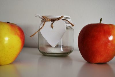 Close-up of apples and jar on table