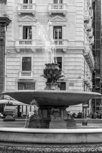 Low angle view of fountain against building in city