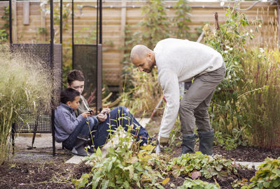 Man gardening at yard with children in background