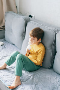 Portrait of cute girl using phone while sitting on sofa at home