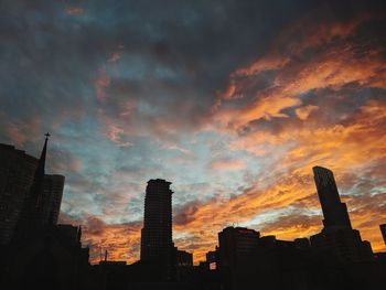 Low angle view of silhouette buildings against dramatic sky