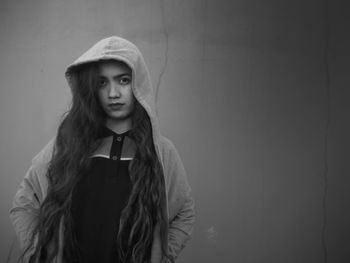 Portrait of young woman standing against wall