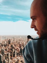 Young man with microphone overlooking cityscape against sky