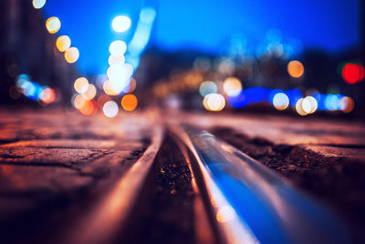 Close-up of railroad track on street in city at night