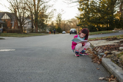 Rear view of woman sitting on road