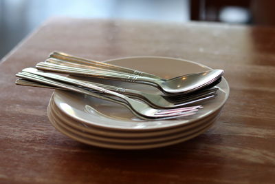 High angle view of forks and spoons in plates on table