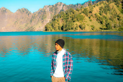 Rear view of man standing against lake