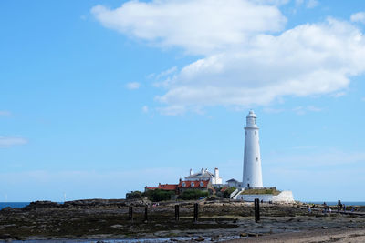 Lighthouse by building against sky