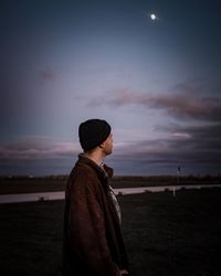 Side view of man looking away against sky during sunset
