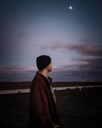 Side view of man looking away against sky during sunset