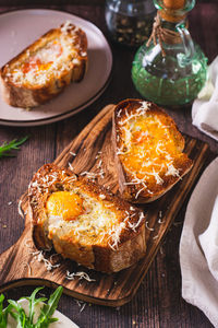 Appetizing brioche baked with egg and cheese on the board vertical view