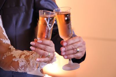 Cropped hands of newlywed couple toasting drinks at ceremony