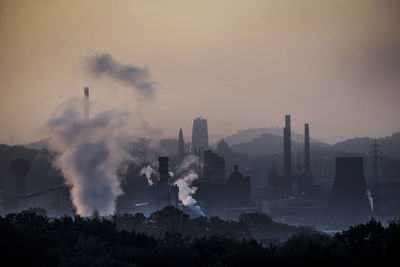 Smoke emitting from factory against sky