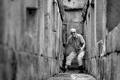 Full length of happy man standing on narrow road