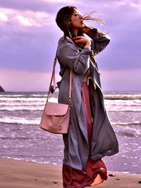 Full length of woman standing at beach against sky