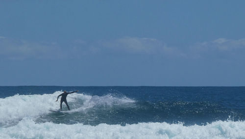 Man surfing in sea against sky