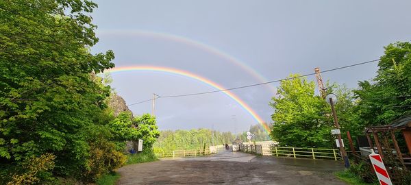 Scenic view of rainbow over trees against sky